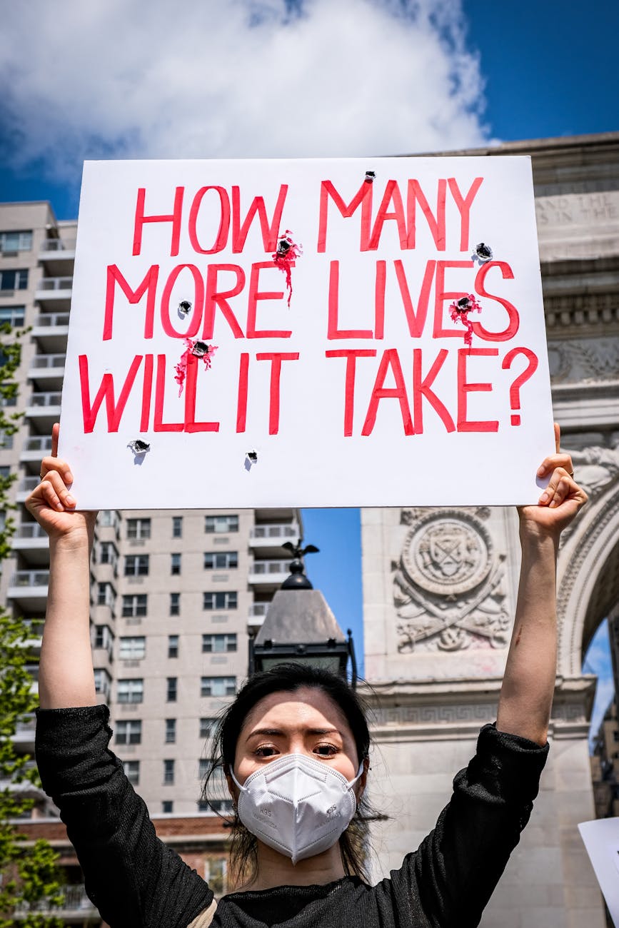woman wearing a face mask holding up a banner at a protest in city